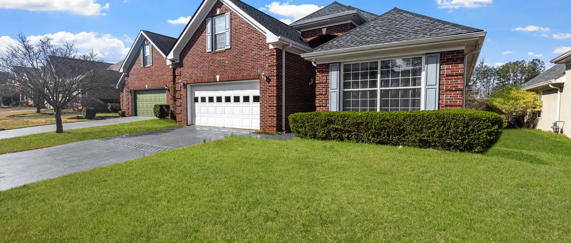 After: the same property with a thick green lawn and clipped foundation shrubs