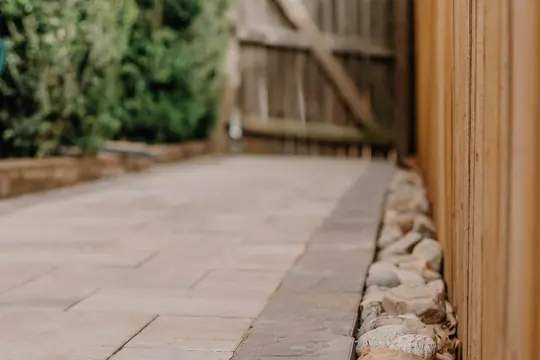 Bluestone walkway edged in river stone beside a cedar fence