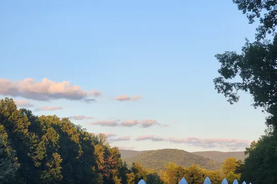 White post and rail fence running along an open field at sunset