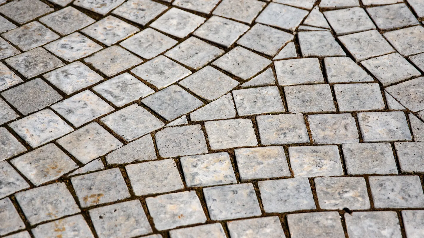 A paver pool deck laid in a running bond pattern beside a rectangular pool
