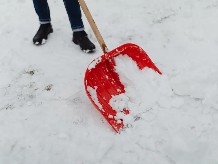 A compact loader clearing banked snow from a driveway