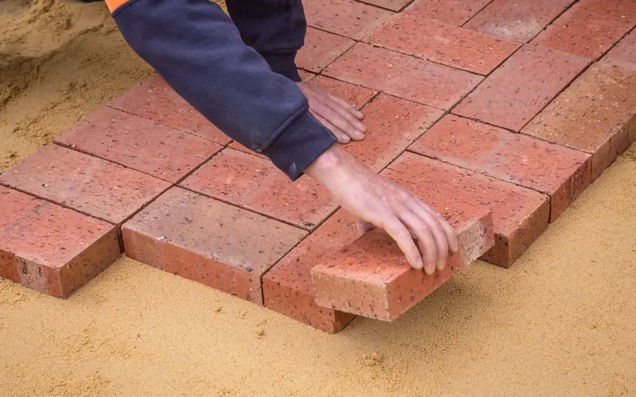 Clay pavers being laid by hand into a curved terrace