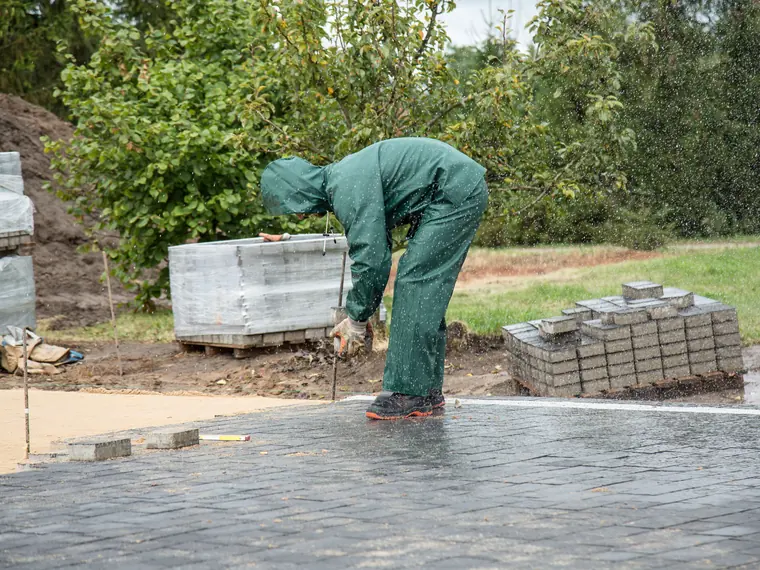 A crew member setting pavers on a freshly screeded base