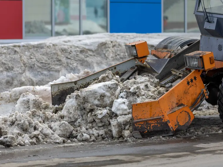 A plow truck clearing a snow covered residential street